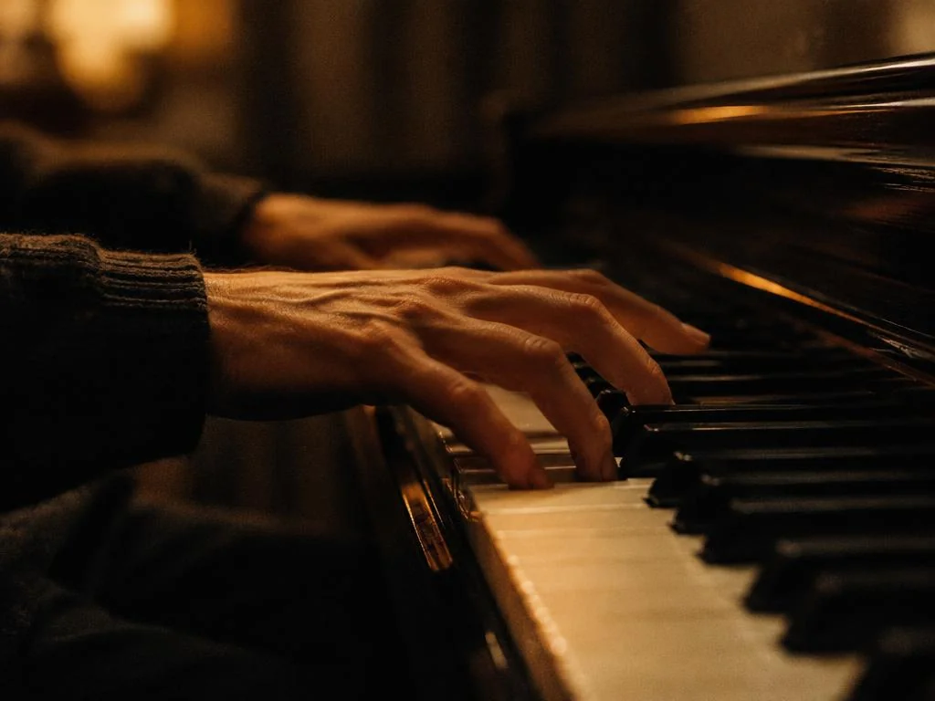 Hands playing a piano in warm light